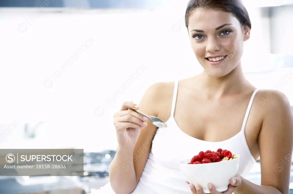 Young woman holding bowl with rasberries