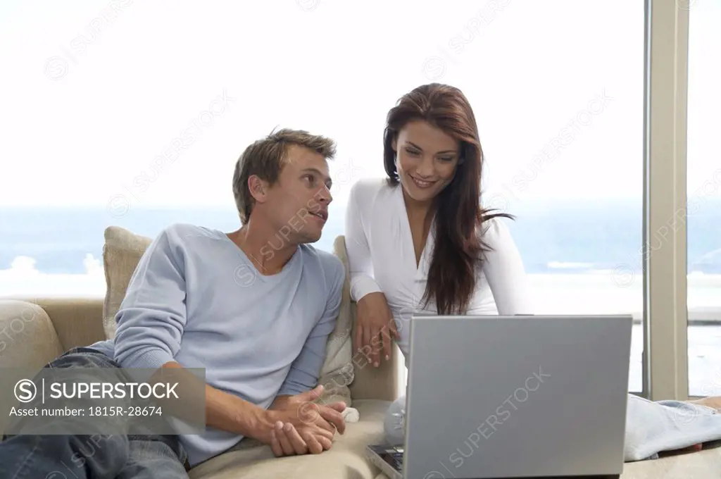 Couple sitting on couch, using laptop