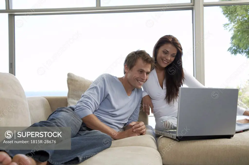 Couple sitting on couch, using laptop
