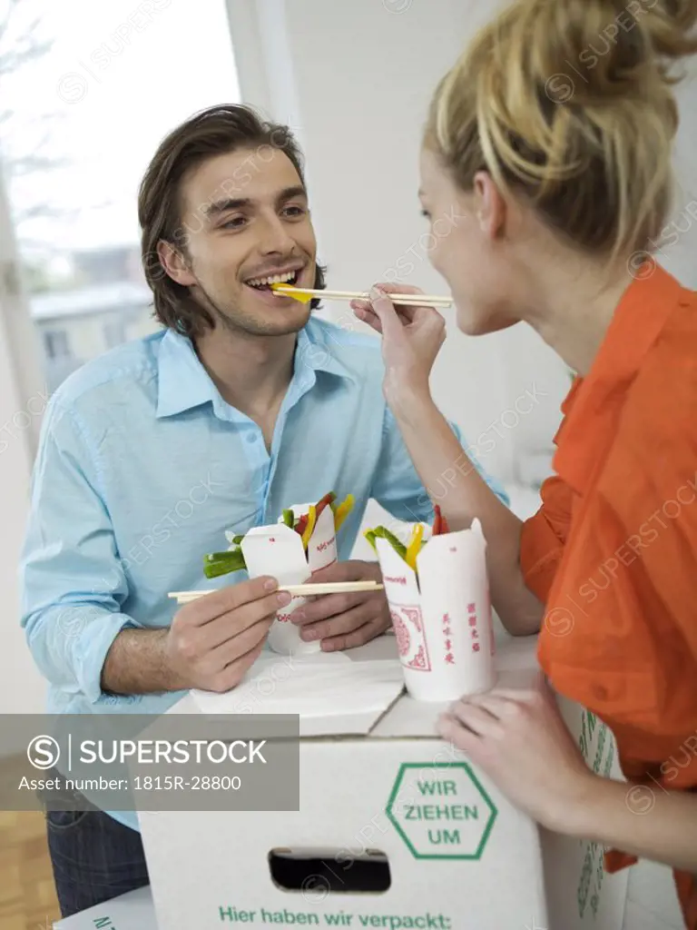 Woman feeding man with chopsticks