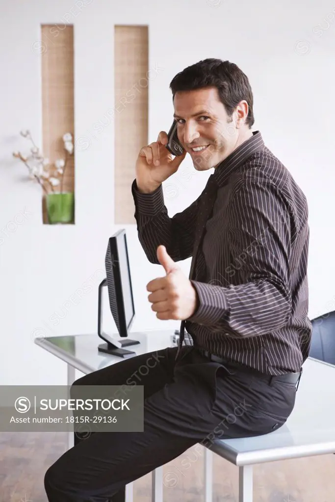 Business man using mobile phone, thumbs up