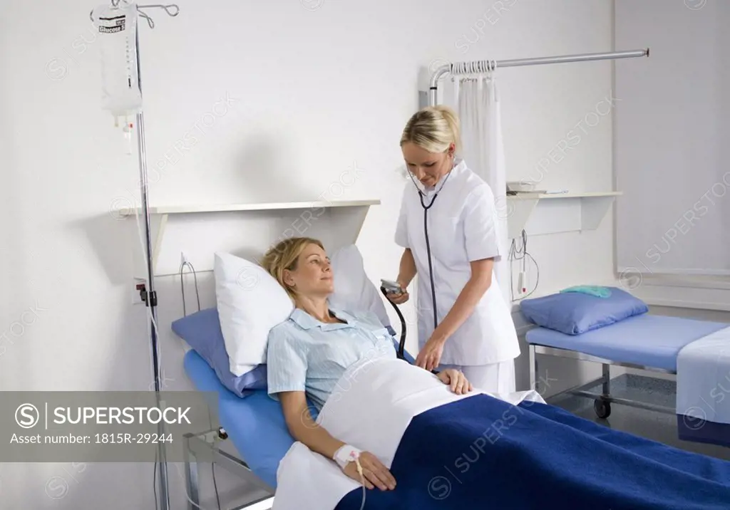 Nurse checking blood pressure of female patient
