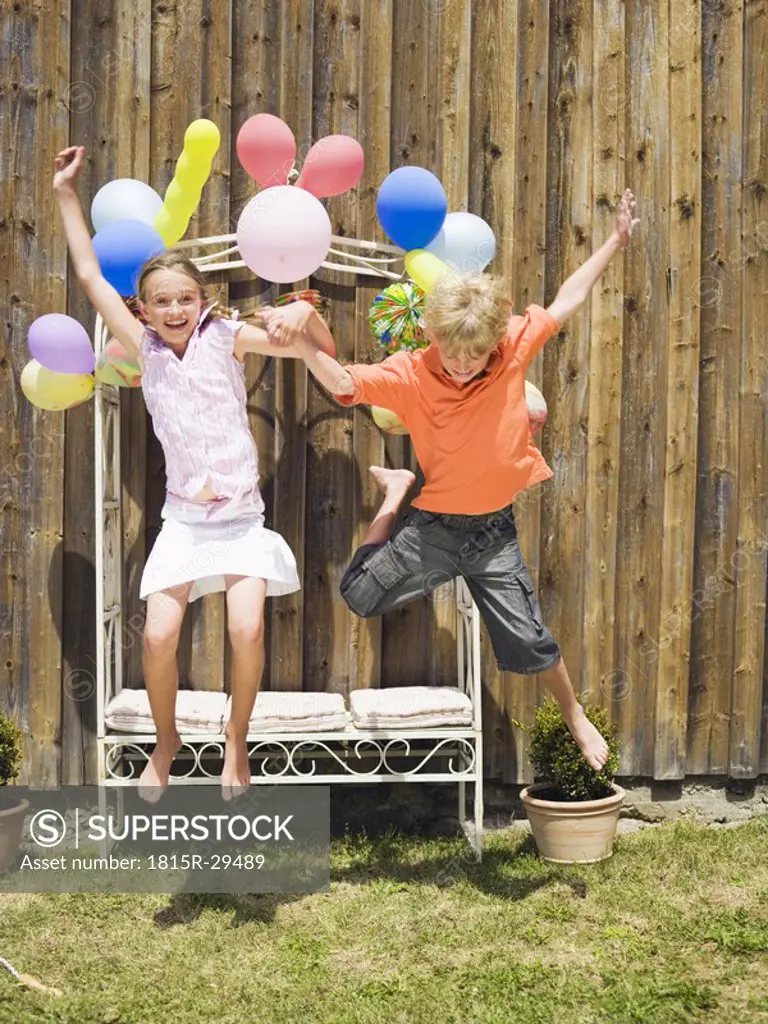 Boy and girl jumping, outdoors