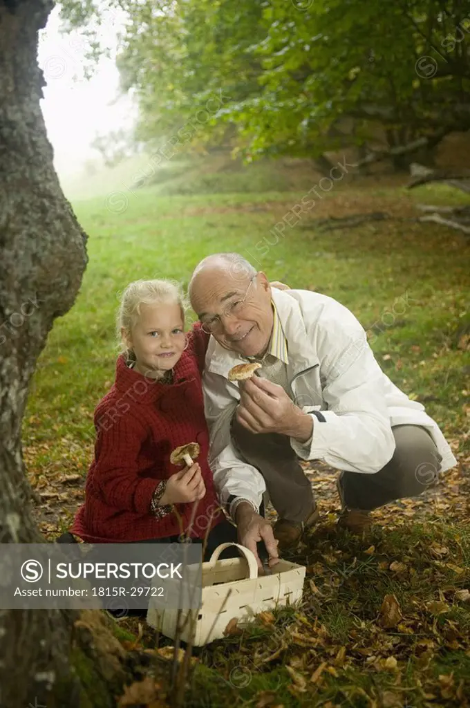 Germany, Baden-Württemberg, Swabian mountains, Grandfather and granddaughter searching mushrooms in the forest, portrait