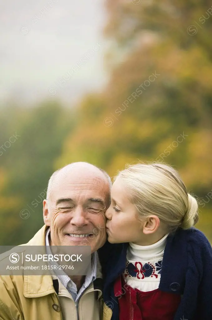Germany, Baden-Württemberg, SwaGrabian mountains, granddaughter kissing grandfather, portrait