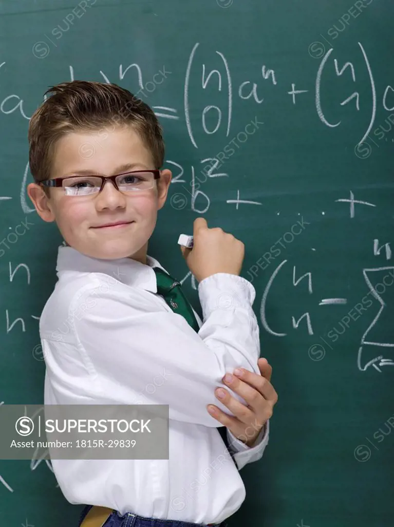 Boy 10-11 in front of blackboard, smiling, portrait