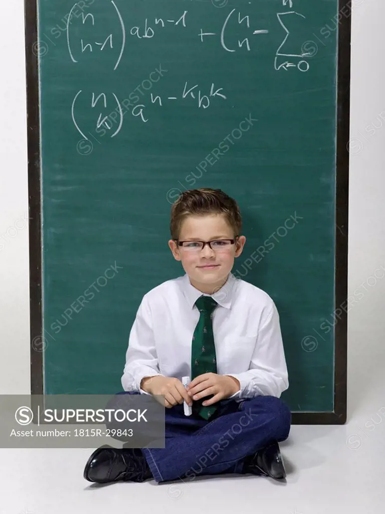 Boy 10-11 sitting in front of blackboard, portrait