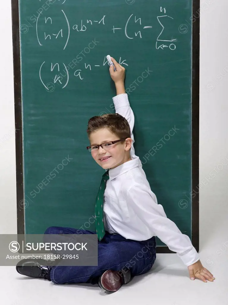 Boy 10-11 sitting in front of a blackboard, portrait