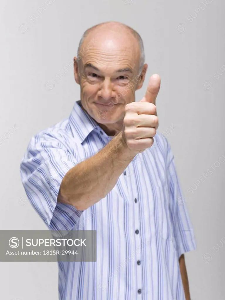Senior man giving thumb up, portrait, close-up