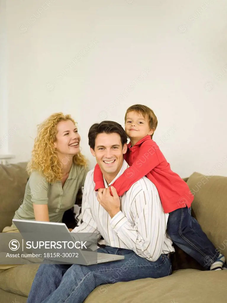 Young family in living room, father using laptop
