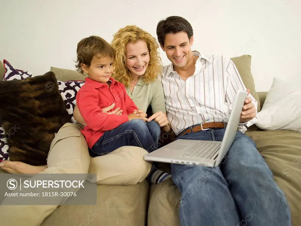 Young family in living room, father using laptop