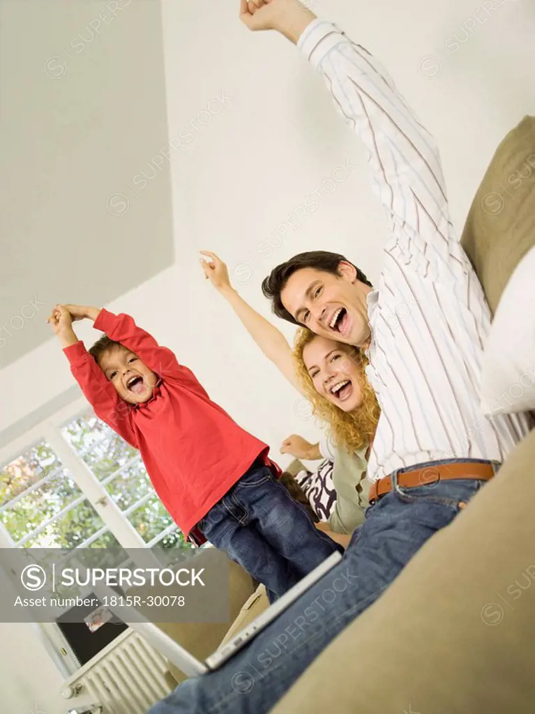 Young family in living room, cheering