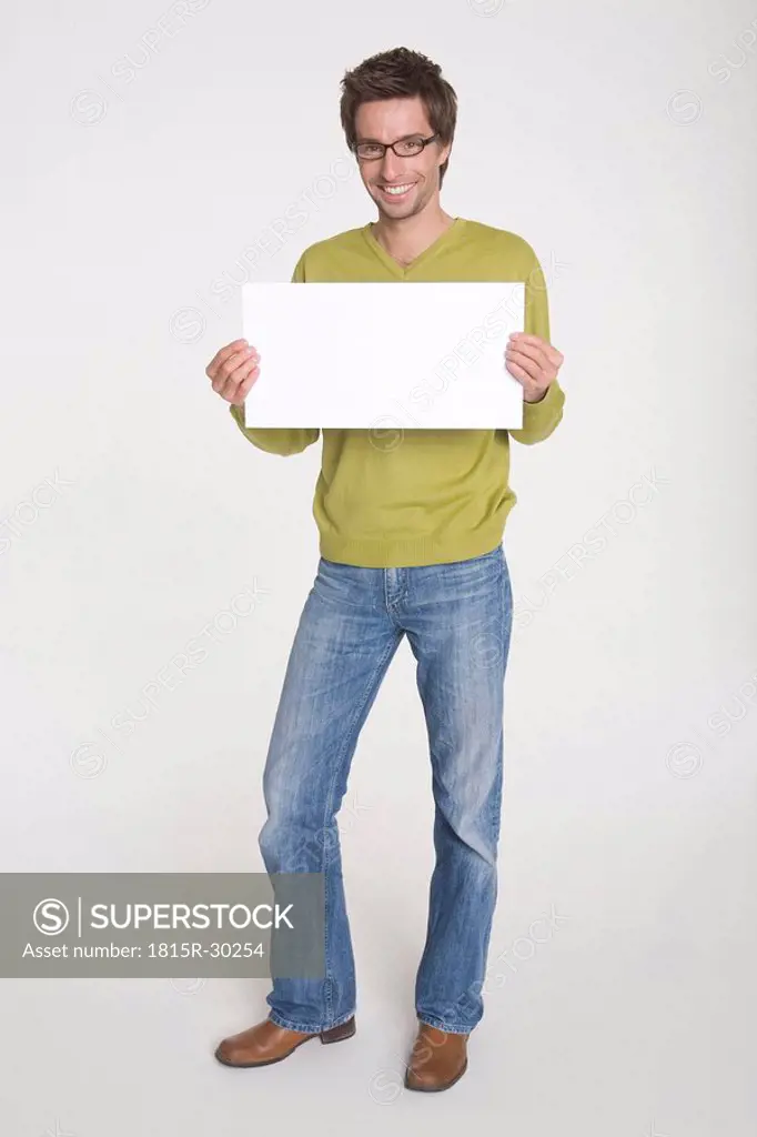 Young man holding blank white board, portrait