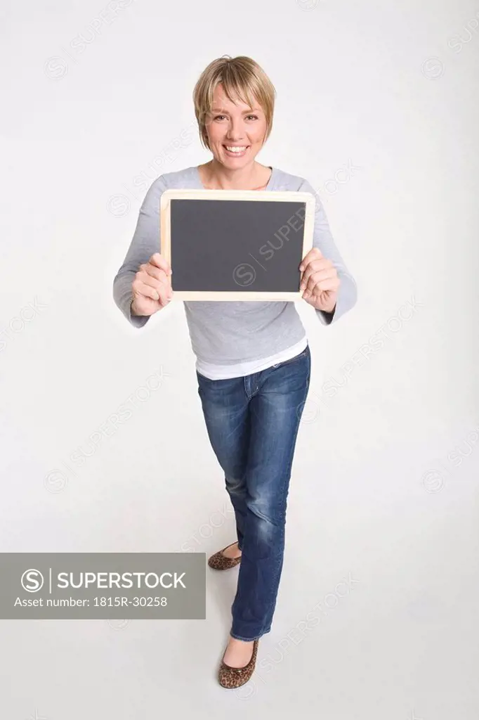 Young woman holding blackboard, smiling, portrait