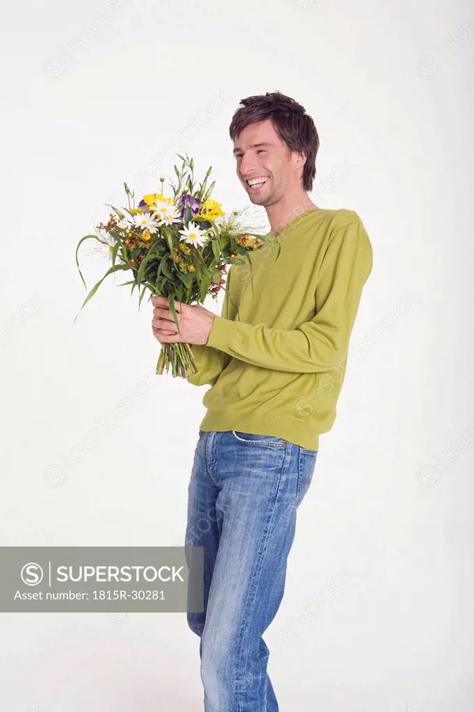 Young man holding bunch of flowers, portrait, smiling