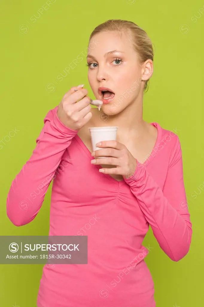 Young woman eating yoghurt, portrait