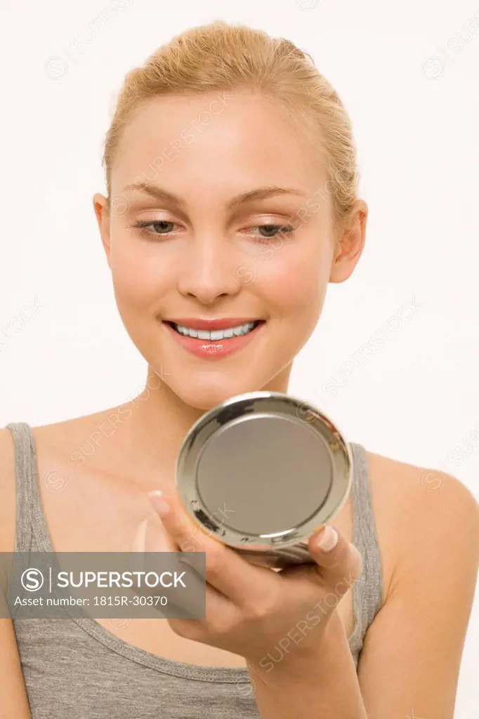 Woman looking at self in make-up mirror, portrait