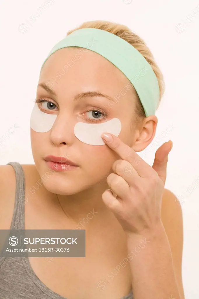 Woman applying adhesive plaster over nose, portrait