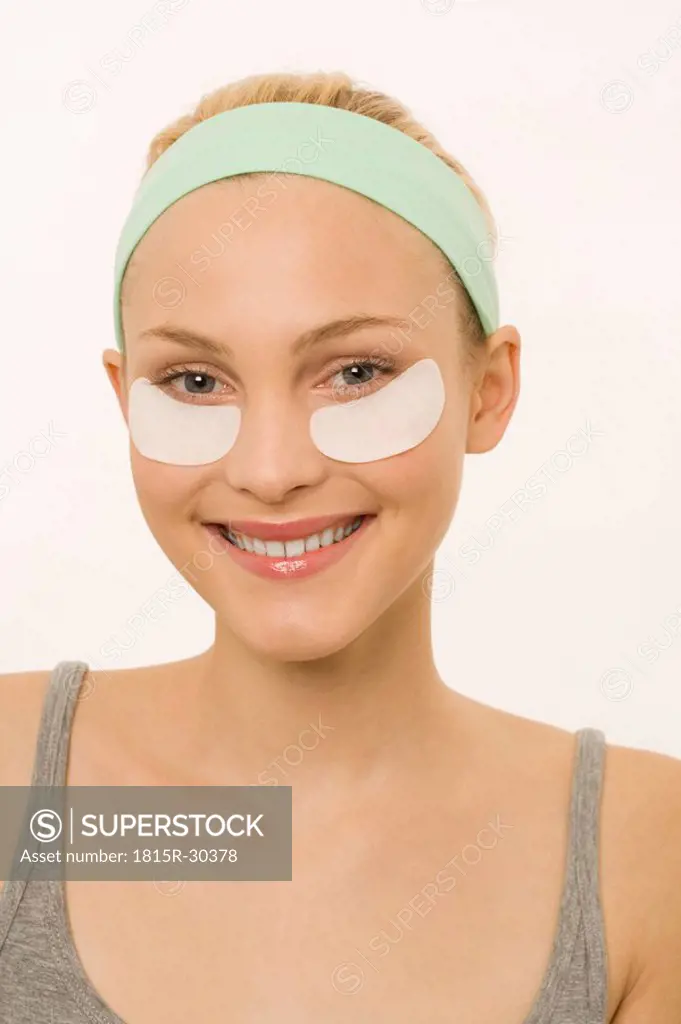 Young woman with eye treatment mask, portrait