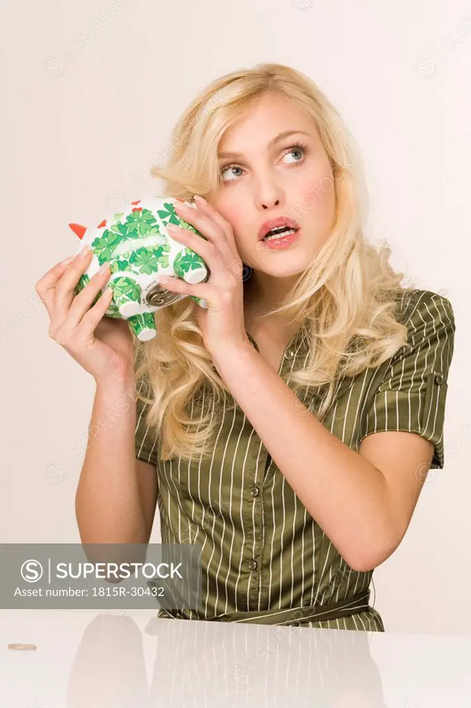 Blonde woman holding piggy bank, portrait