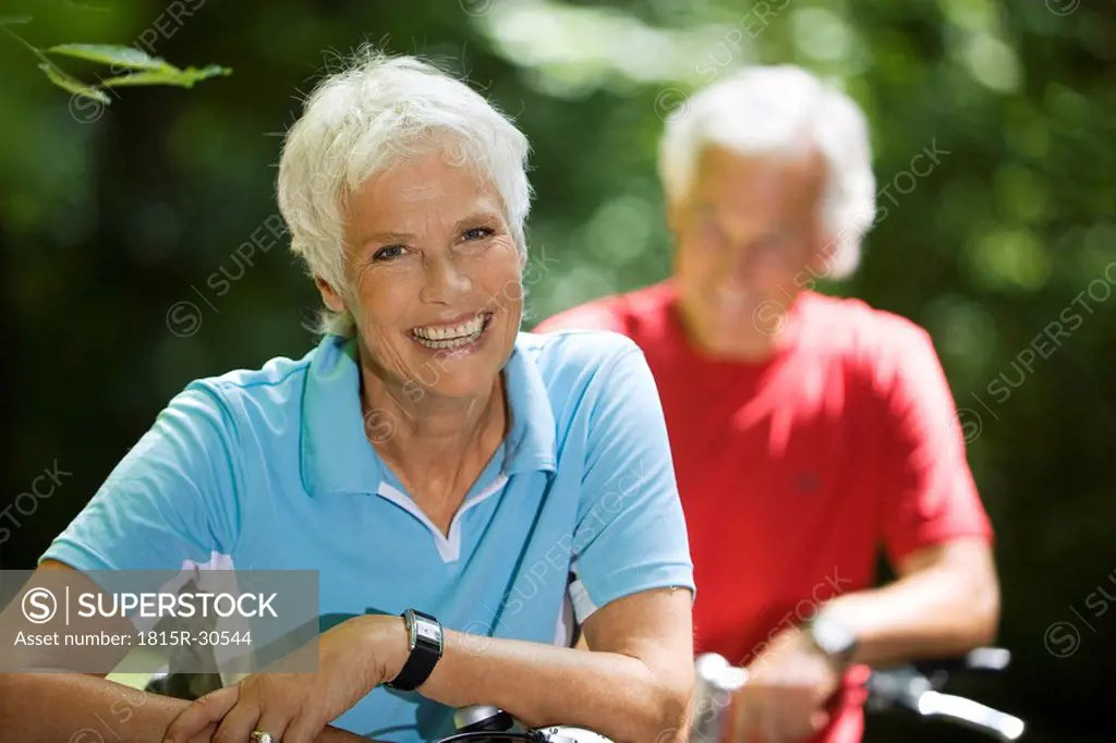 Senior couple with bikes, woman smiling, portrait