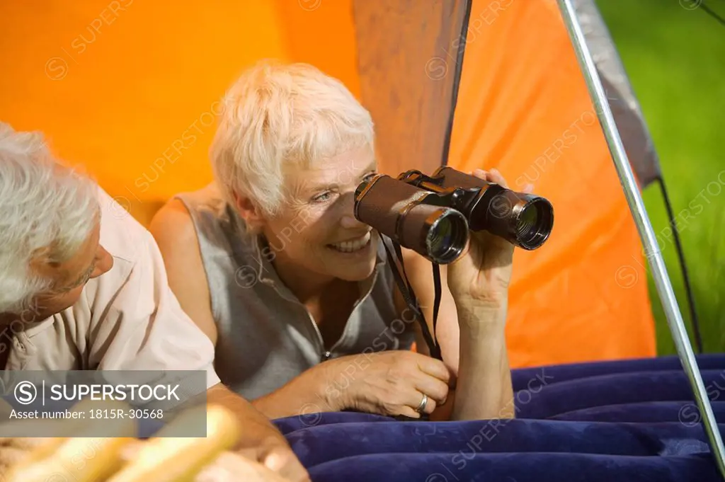 Senior couple camping, woman with field glasses, portrait