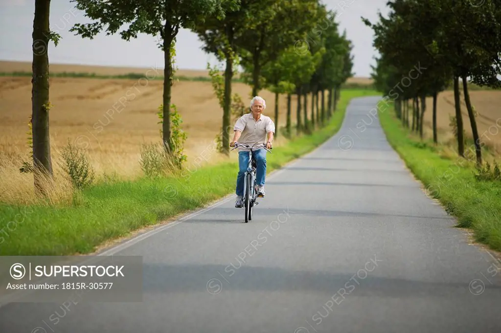 Senior man biking on road