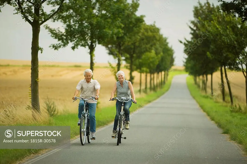 Senior couple biking on country road