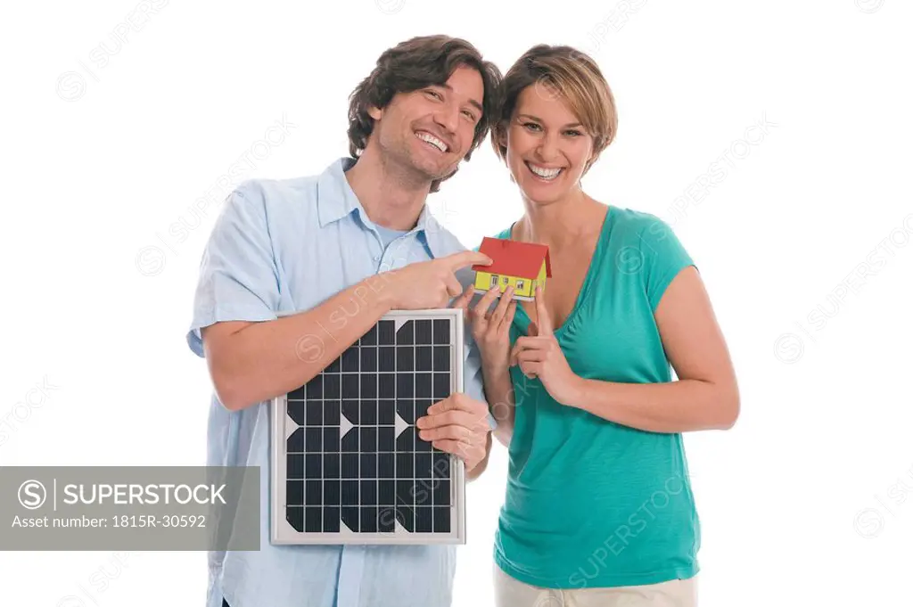 Couple holding solar panel and house