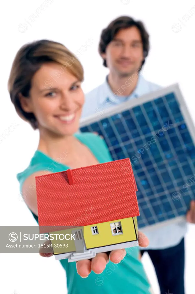 Couple holding solar panel and house