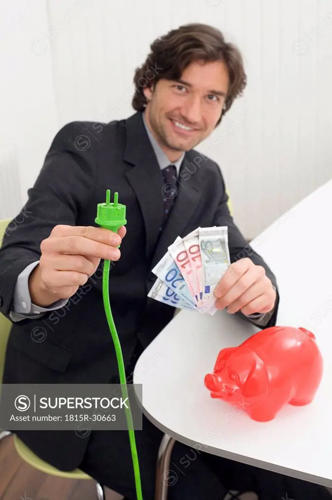 Man holding green plug and banknotes