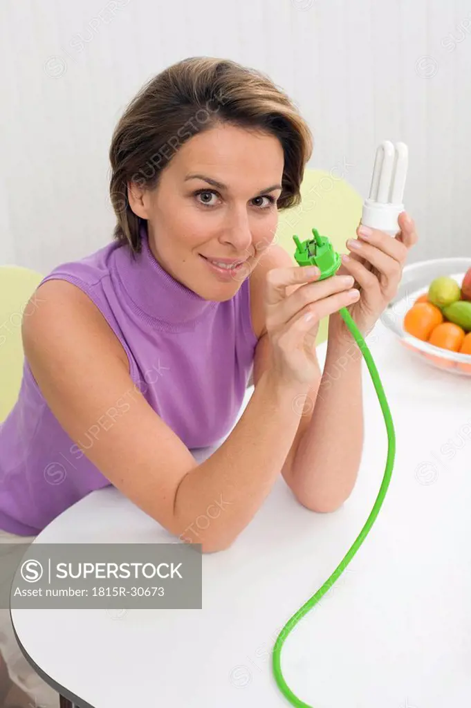 Woman holding green plug and bulb