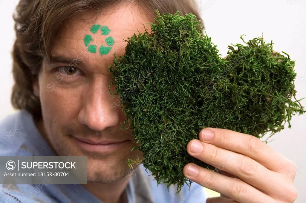Man with green sign on forehead,holding grass heart, portrait