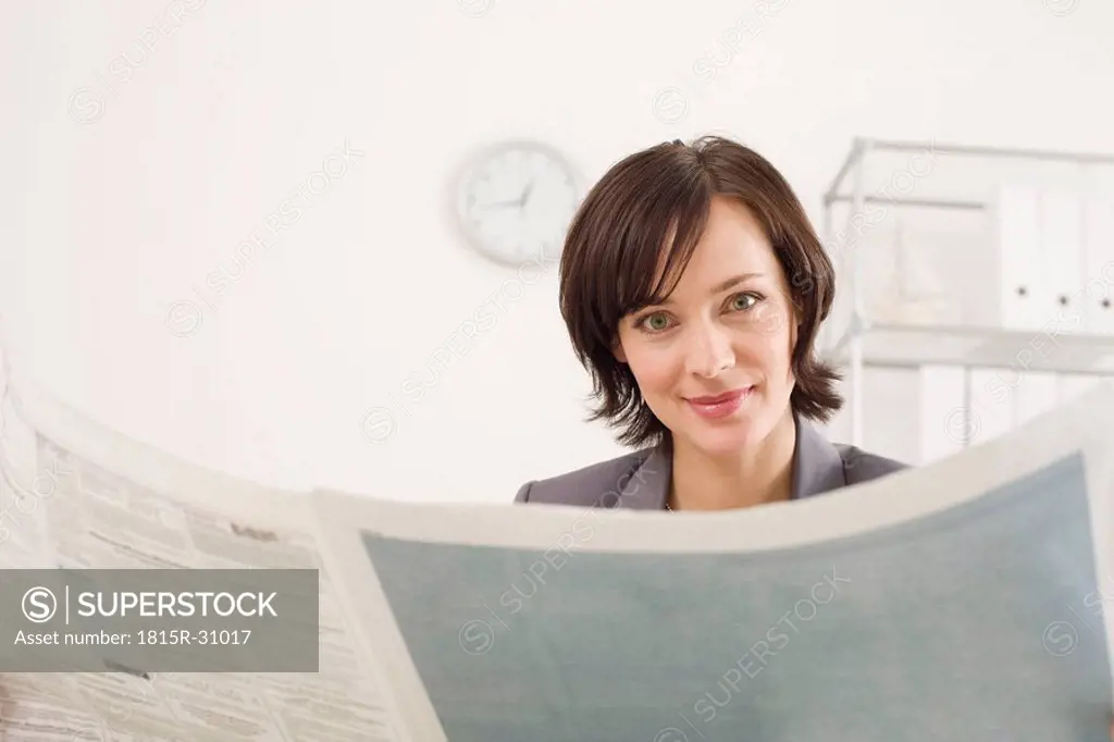 Businesswoman reading newspaper, portrait