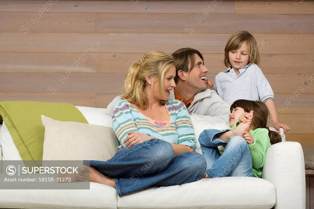 Family sitting on sofa, smiling, portrait
