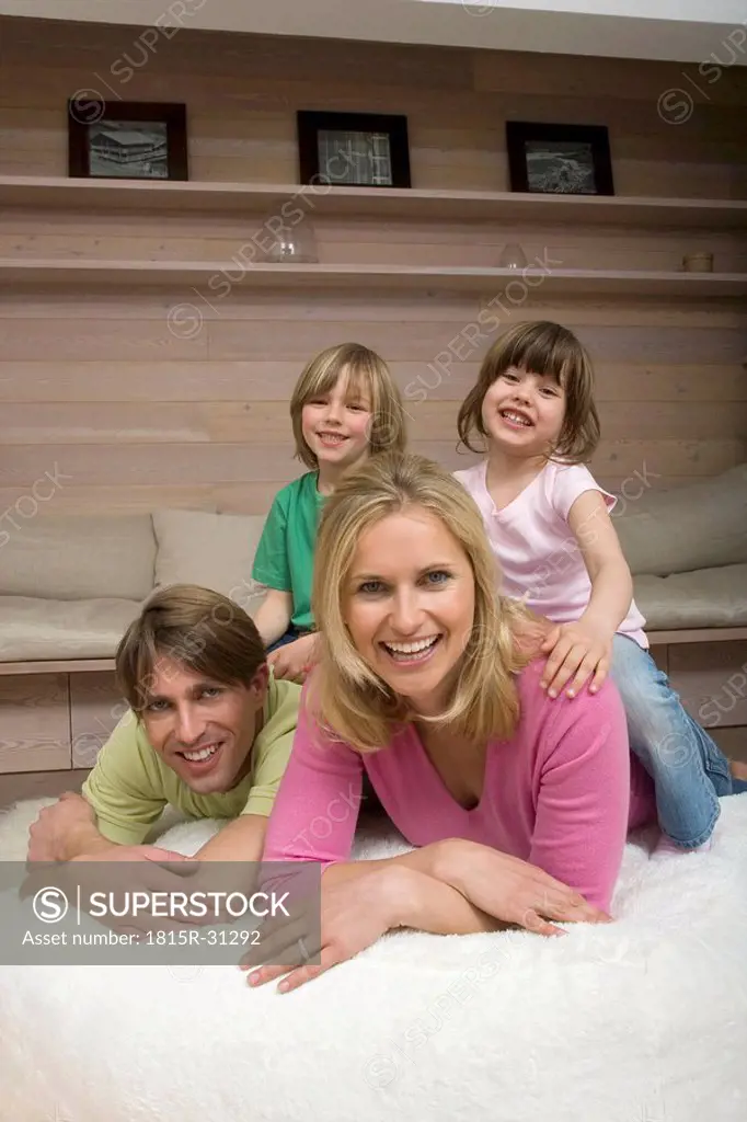 Family in living room, children sitting on parent´s neck, smiling, portrait