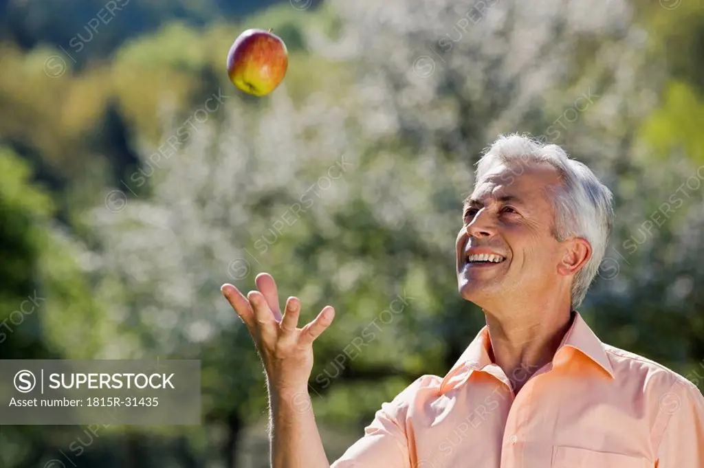 Germany, Baden Württemberg, Tübingen, Senior man playing with apple, portrait