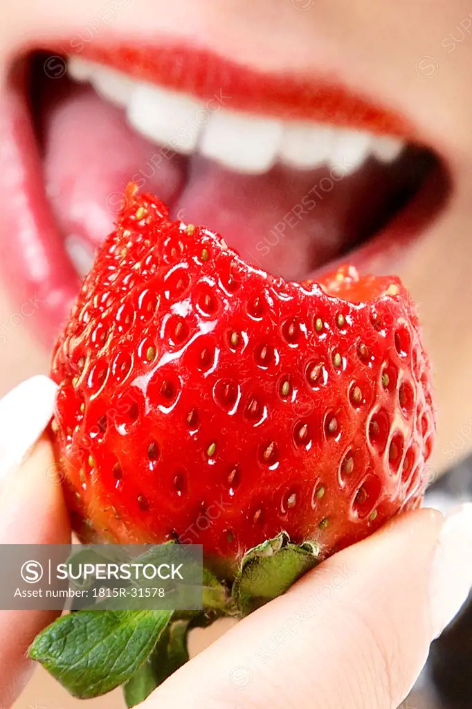 Woman eating strawberry, close-up
