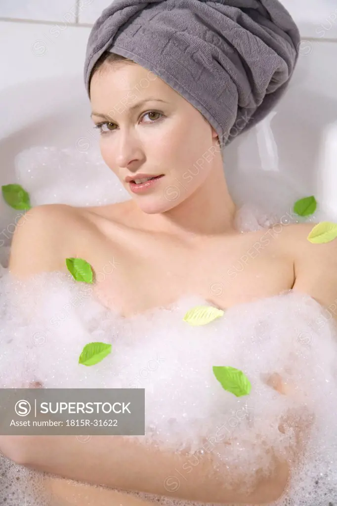 Young woman taking a bubble bath, close-up, portrait