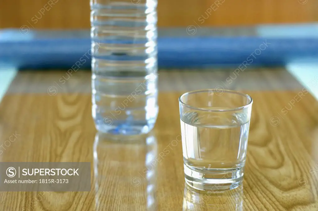 Glass of water by plastic bottle, close-up