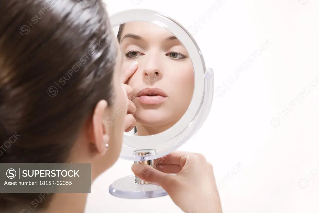 Young woman looking into mirror, portrait