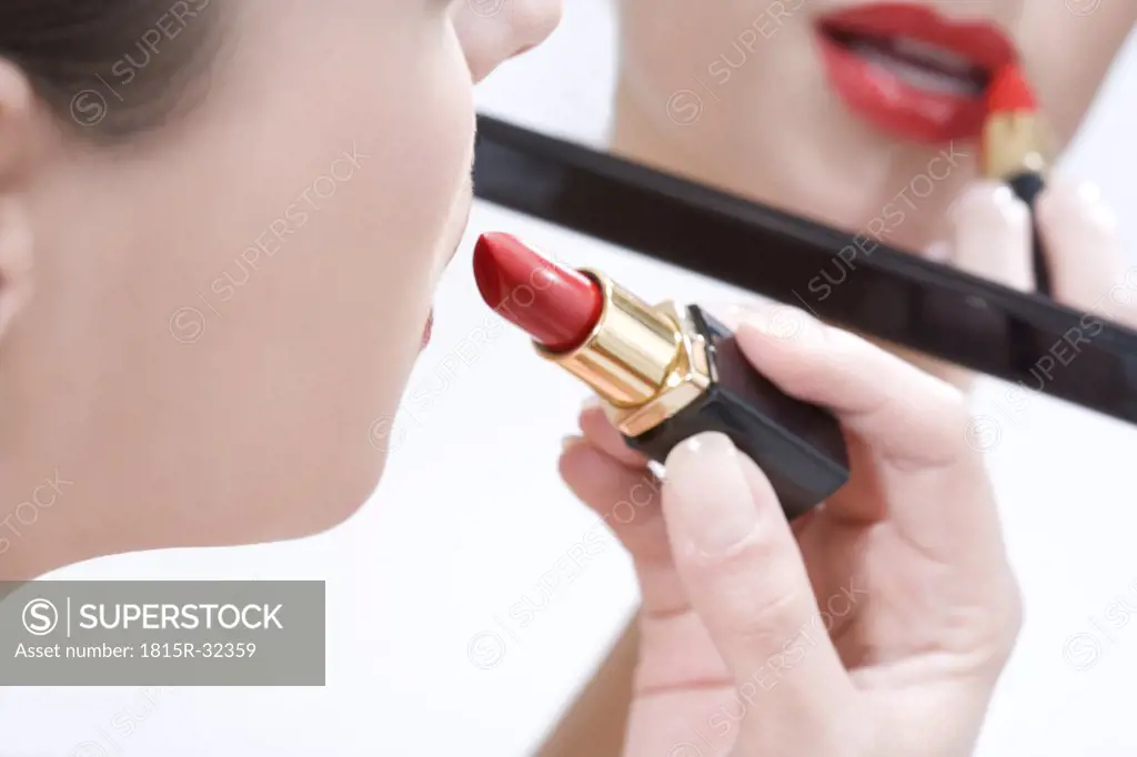 Young woman putting makeup on, portrait