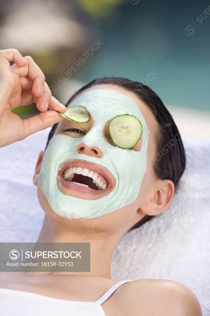 Young woman with face mask and cucumber slices, portrait