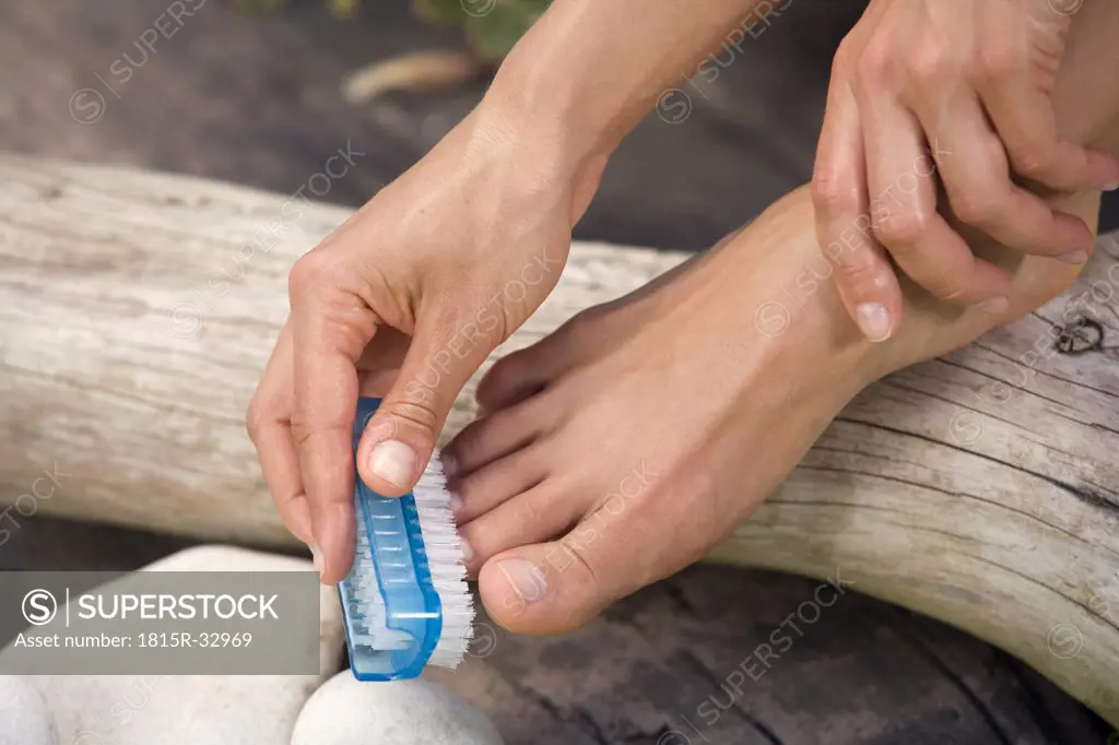 Woman brushing her feet, low section