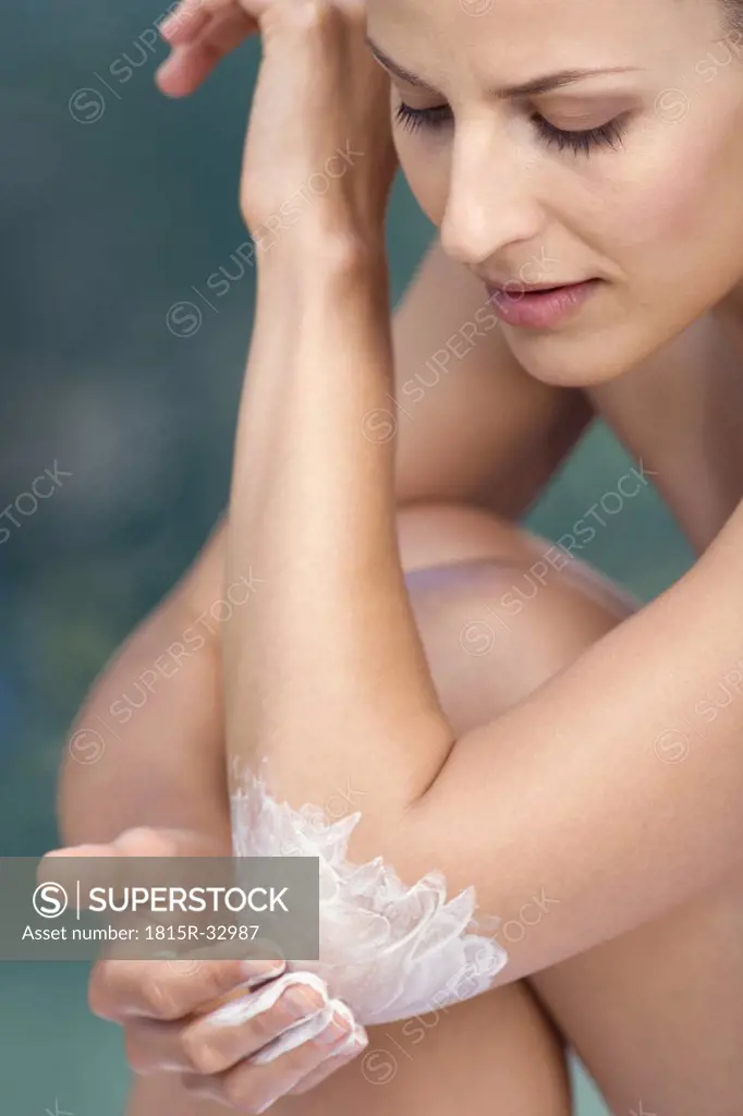 Woman Applying Skin Cream to Elbow, portrait