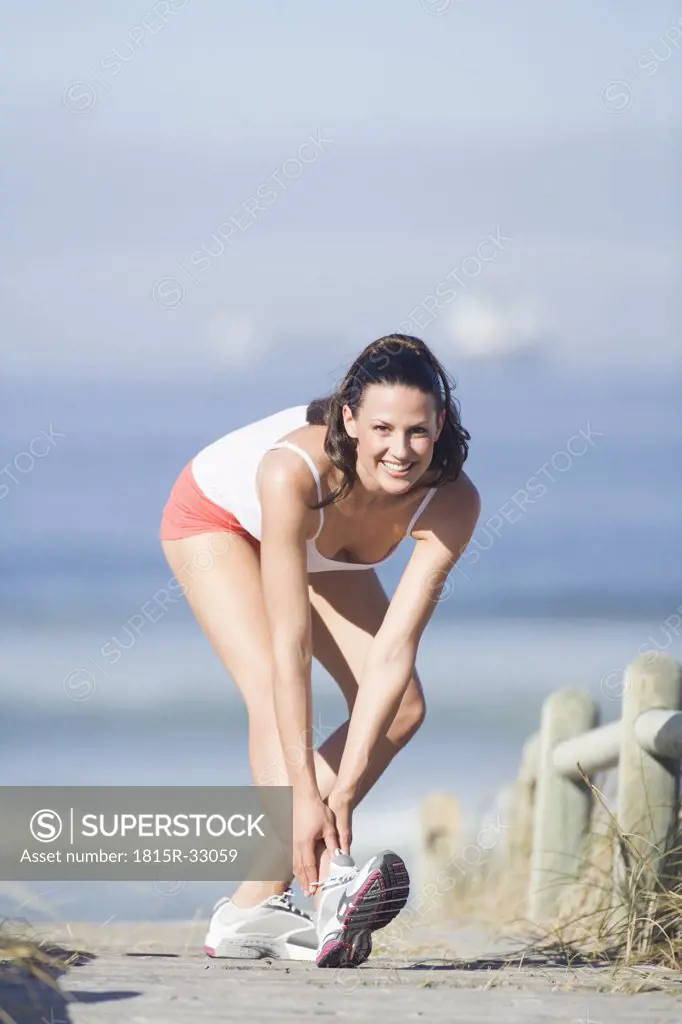 Young woman stretching leg, smiling, portrait