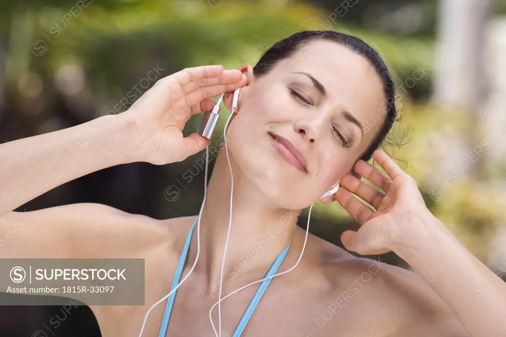 Young woman listening to MP3-Player, eyes closed, portrait