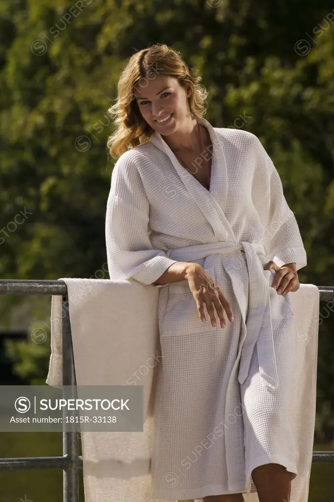 Woman wearing bath robe, leaning on railing