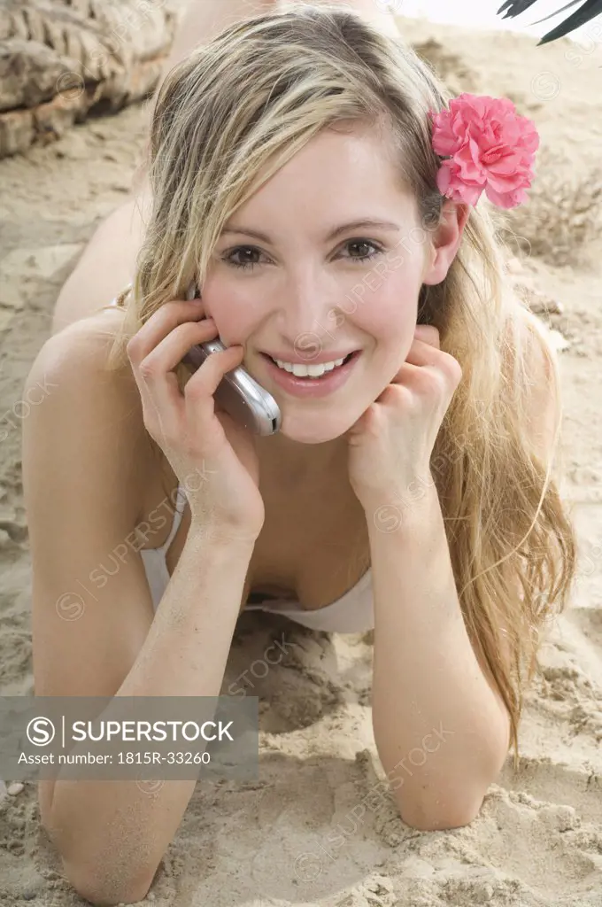 Woman lying on beach, using mobile phone