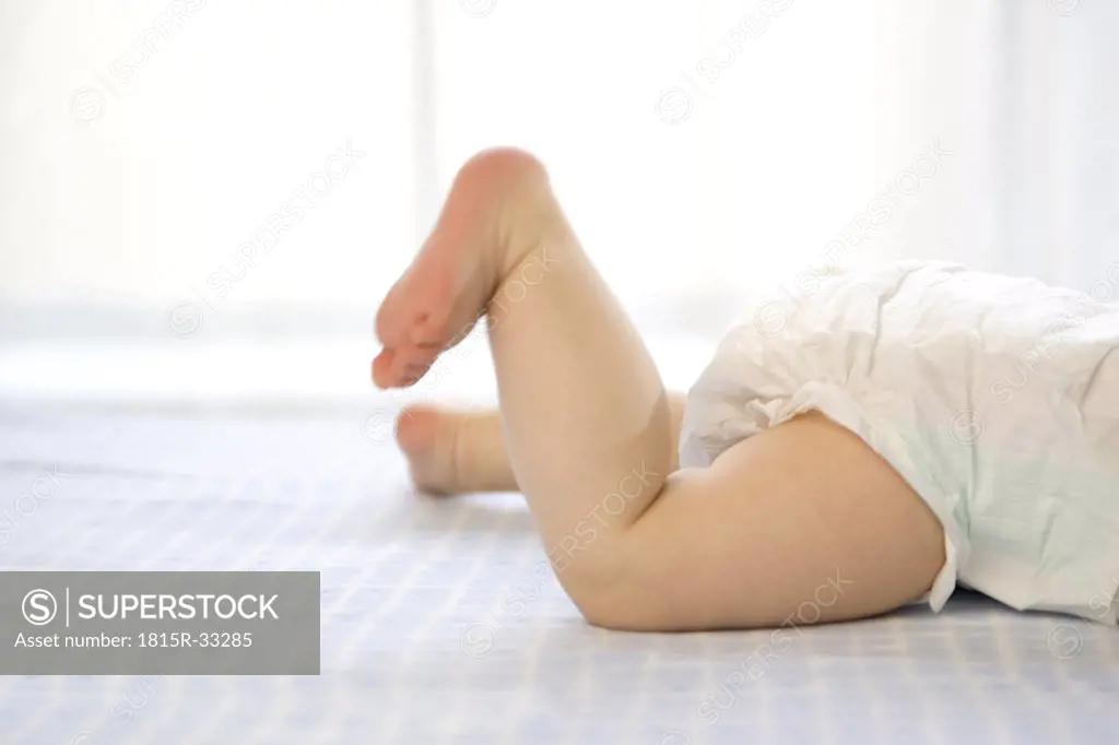 Baby boy ( 6-12 months) lying on front, side view, low section